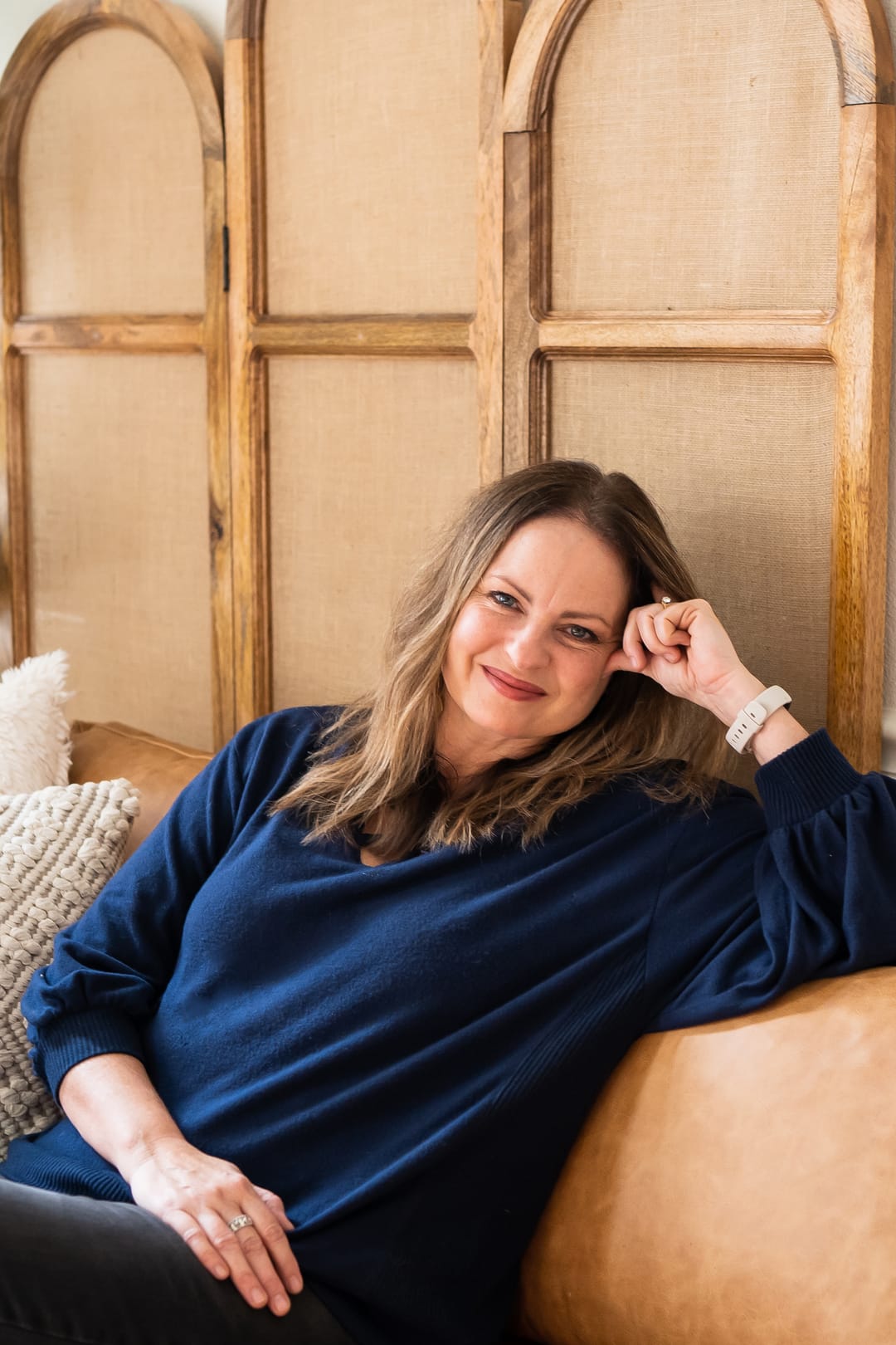 Jen Bell, Fresno-based painter and instructor, seated on a leather sofa.